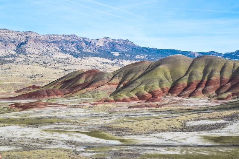 Colorful earth mounds with mountain in background and blue sky