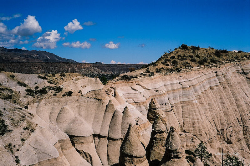 Cone-shaped tan hoodoos beneath a blue sky.