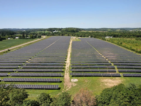 hundreds of solar panels in a grassy field