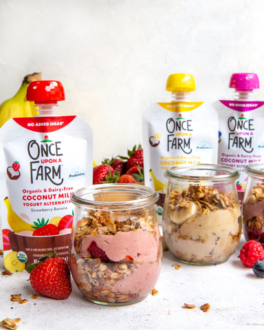 three parfaits in jars, next to three Once Upon a Farm Dairy-Free Coconut Yogurt Alternative pouches