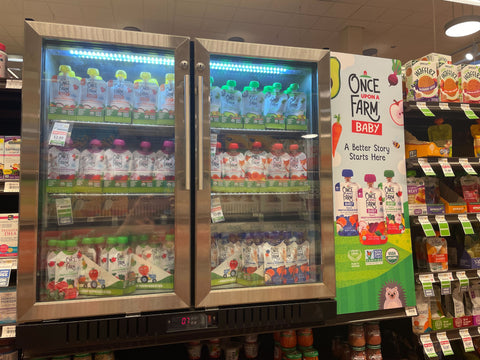 once upon a farm-branded baby cooler, filled with baby food pouches in the baby aisle within a grocery store