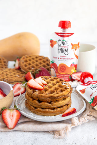 Stack of waffles, topped with strawberries, next to two Once Upon a Farm Strawberry Patch pouches