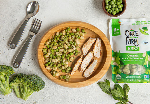 sliced chicken on a plate with the Once Upon a Farm Broccoli, Pea & Navy Bean Meal