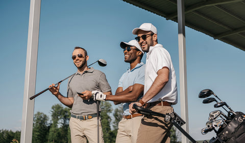 three men holding golf clubs and smiling on a sunny day at the golf course