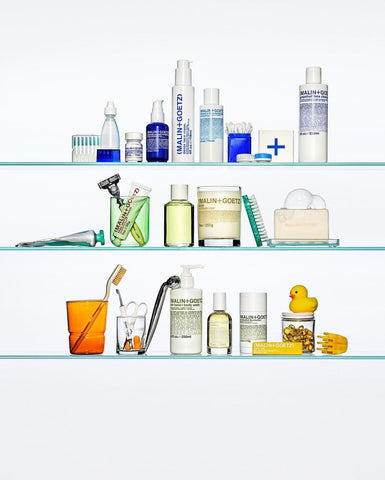 assorted skin care and grooming tools on glass shelves on a white background