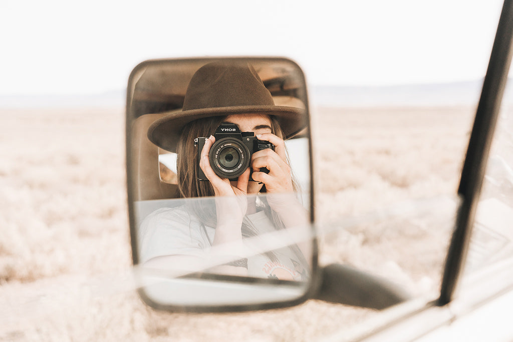 Lauren Williams wearing William Brown hat taking her portrait in the reflection of vans side review mirror