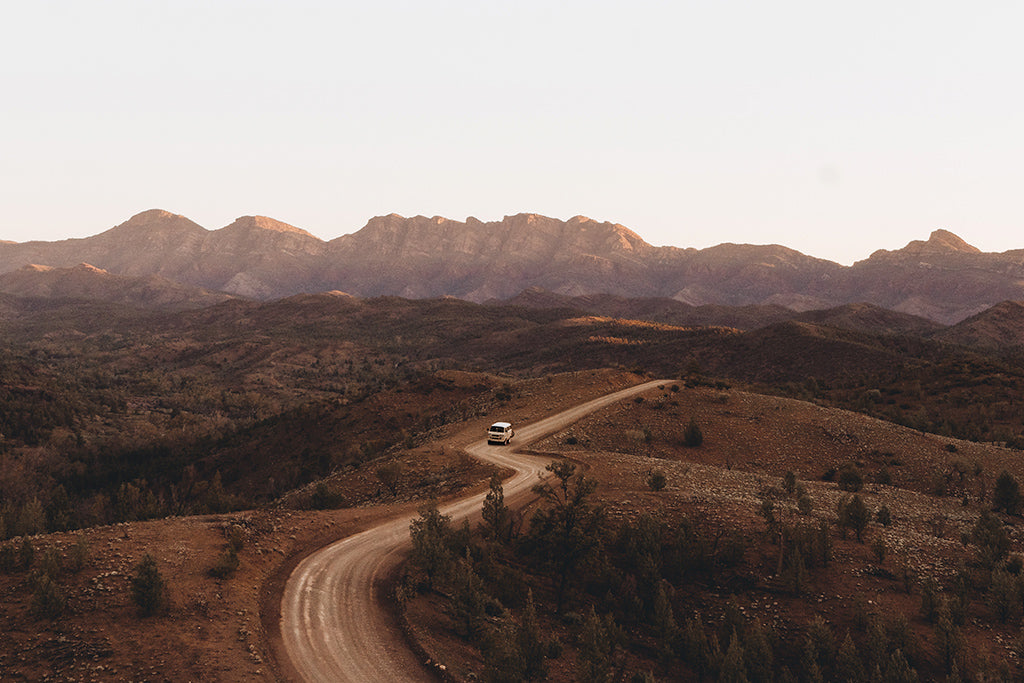 Ariel view of vintage van driving along an s-bend dirt road