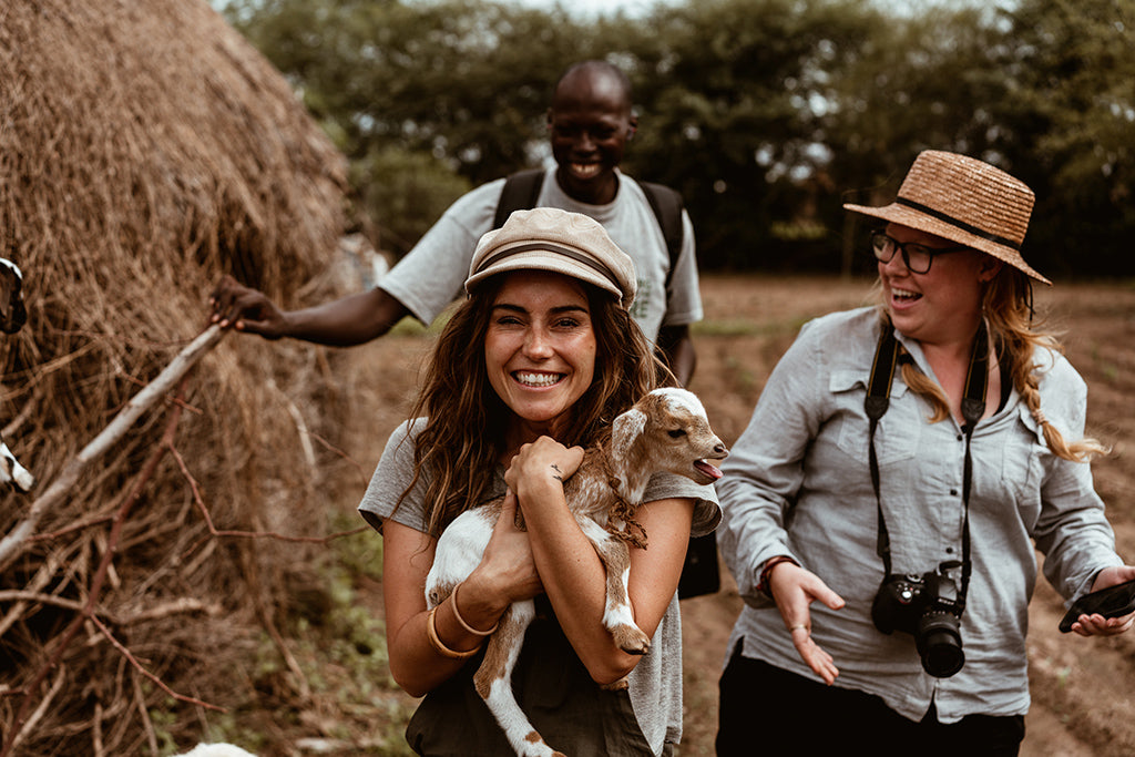 Lauren Williams holds baby goat in Africa wearing Baker Tan cap