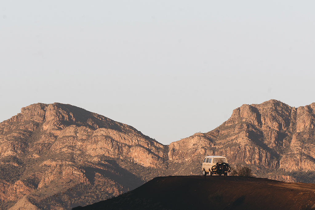 Vintage van with motorbike attached at the back parked stationary among the view of mountains