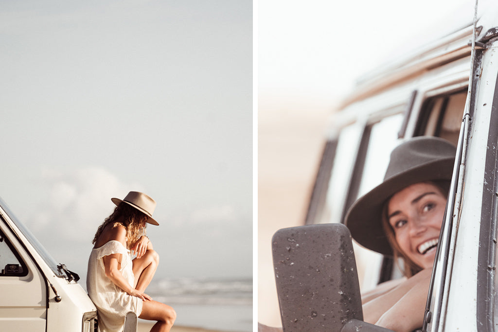 Women wearing widebrim hat sits on the bull bar of her vintage van parked on the sand