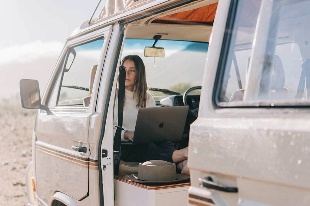 Lauren Williams sitting inside her vintage van working on her laptop