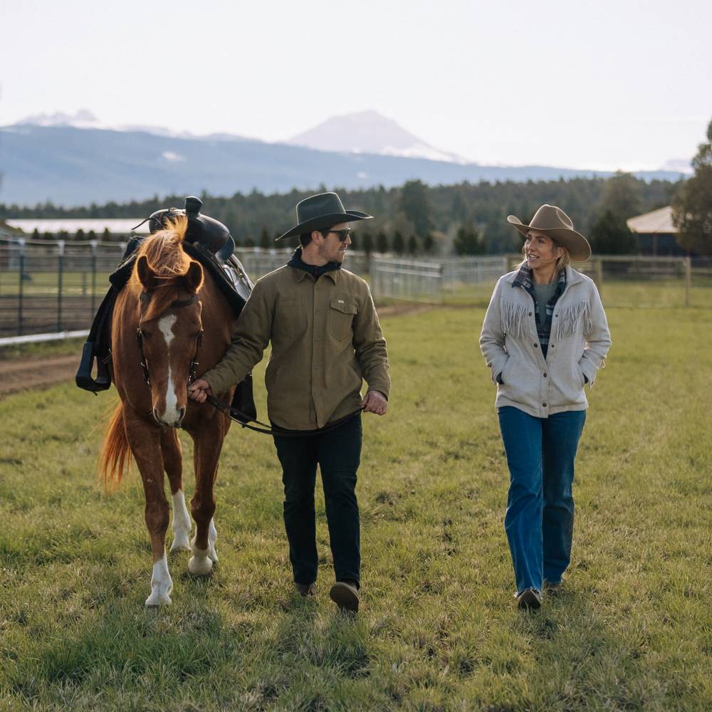 Man and woman walking a horse wearing Buck Smoke Black and Oak Brown cowboy hats