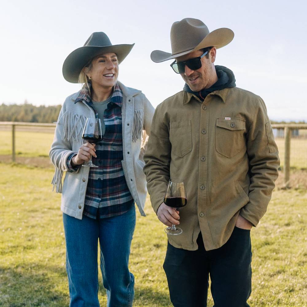 Man and woman wearing Buck Cowboy and cowgirl hats drinking wine sitting on a deck