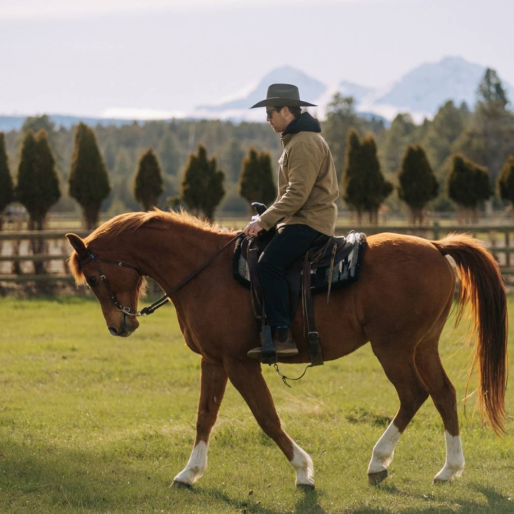 Man riding a horse wearing Buck smoke black cowboy hat