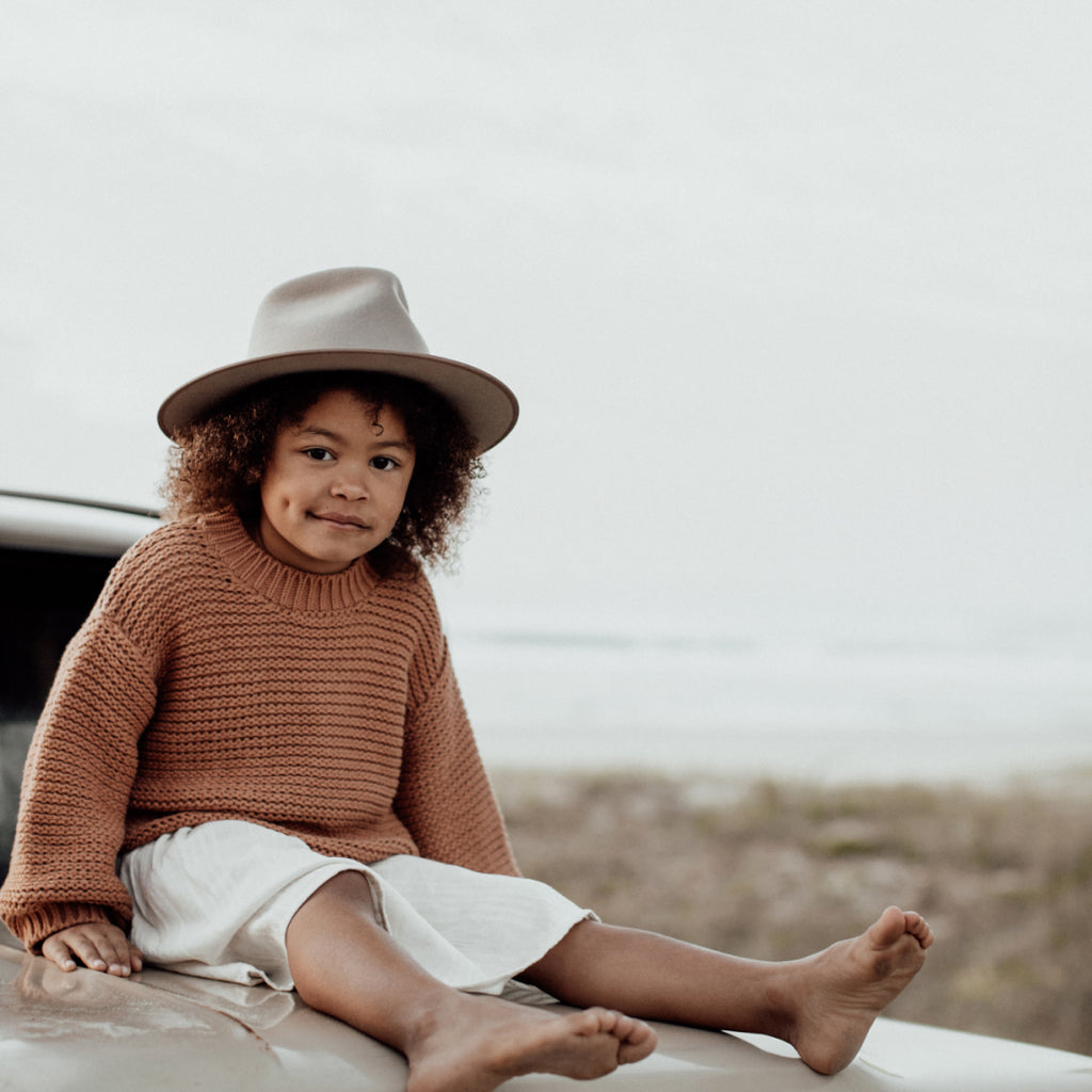 Kid sitting on car wearing a sun hat