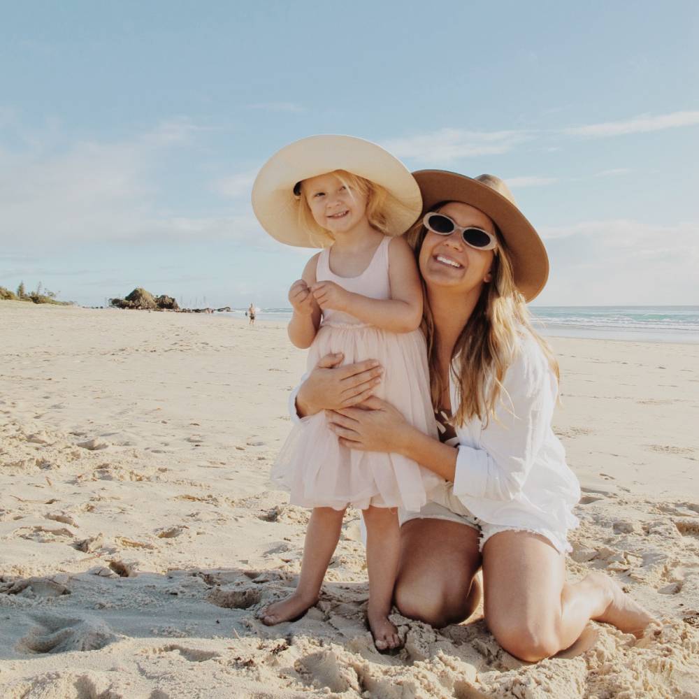 mum and daughter wearing wide brim hats on holiday at the beach