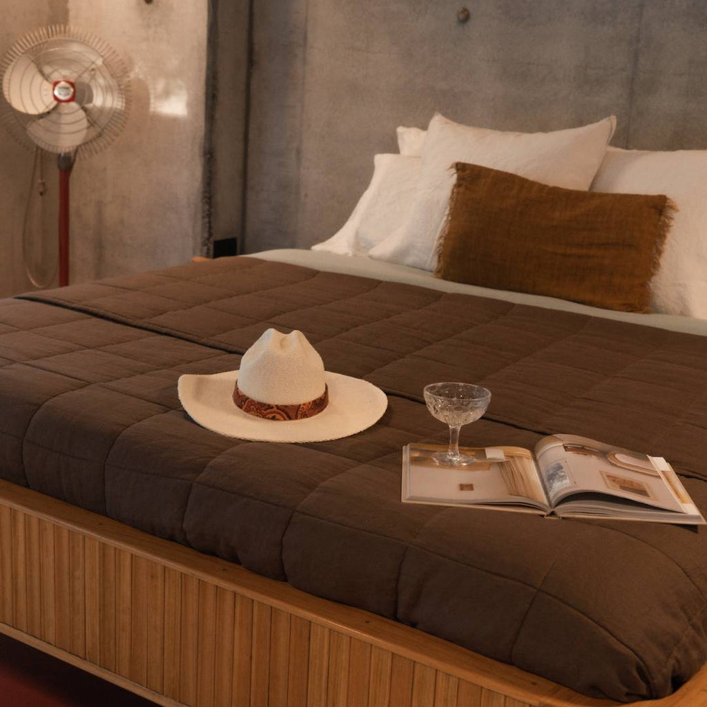 A cowboy hat, cocktail glass and book laid out on top of a bed in a vacation house