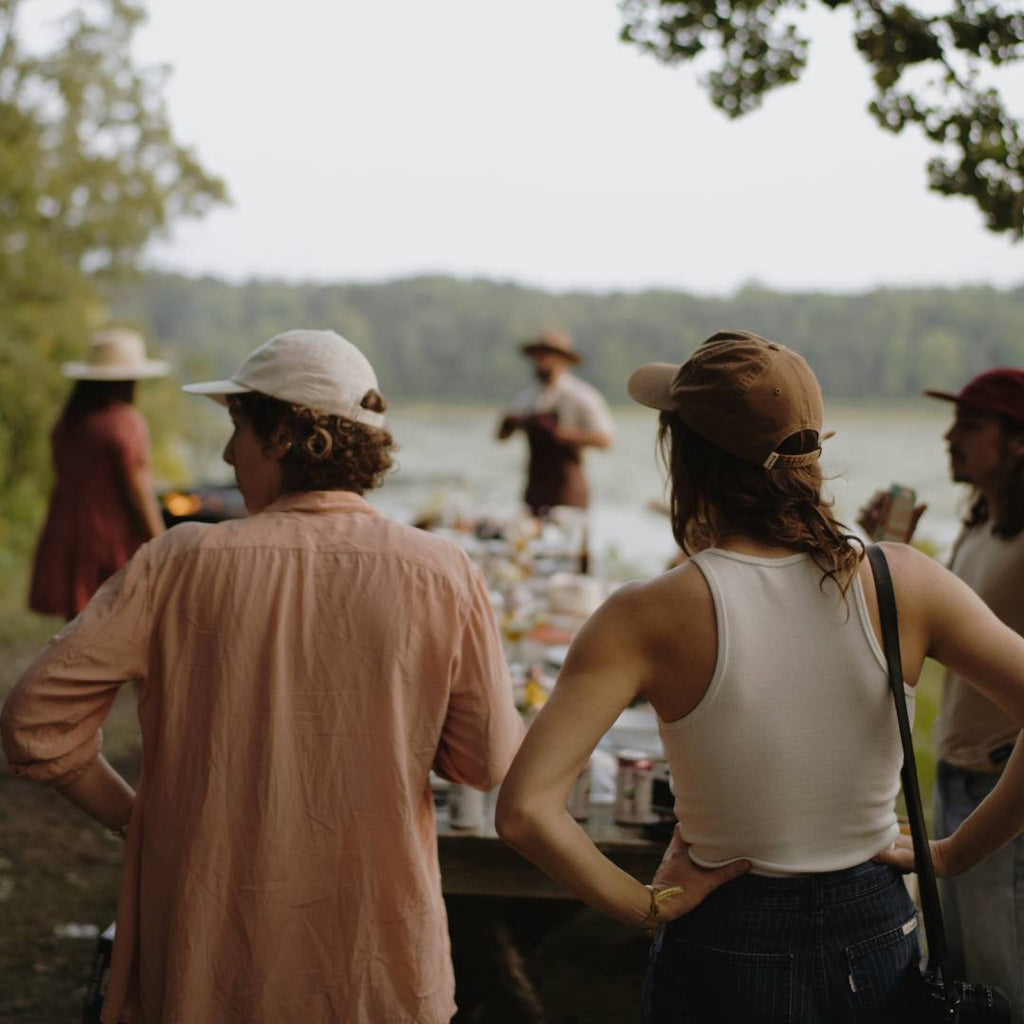 A group of people wearing caps about to sit down at an outdoor dining table