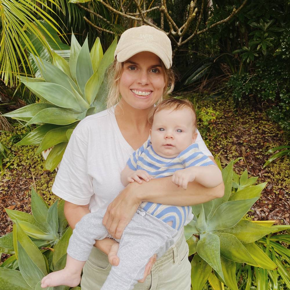 Mum wearing a Parker Bone cap holding her baby while going for a walk outdoors