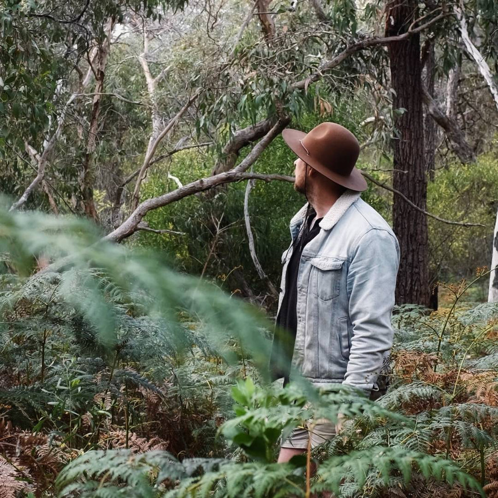 A man with short hair is wearing a wide brim hat while hiking through the Victorian bush