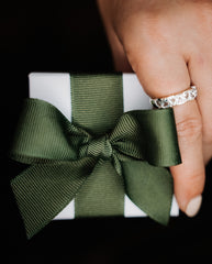 hand holding a jewellery box packaged with a safari green bow