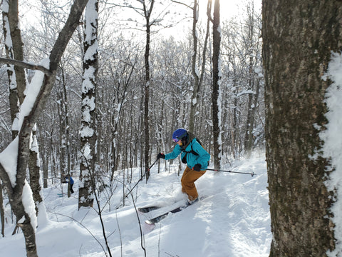 Devin skiing in the woods at Sugarbush, wearing her Alixandra Barron Designs upcycled rubber adventure jewelry