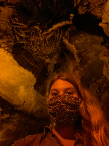 Aubrey exploring a cave, wearing her ABD Culture rubber, adventure jewelry.