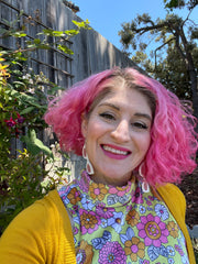 Portrait of Kaelen, founder of Darling Marcelle. Image shows a white woman with pink hair wearing pink and orange clothes.