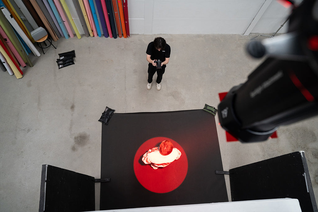 Bird's-eye view of photographer taking photos of a male model under a red spotlight  