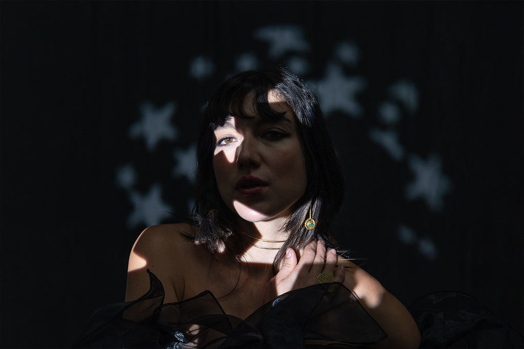 Female model in front of a black backdrop with a stars spotlight covering her face