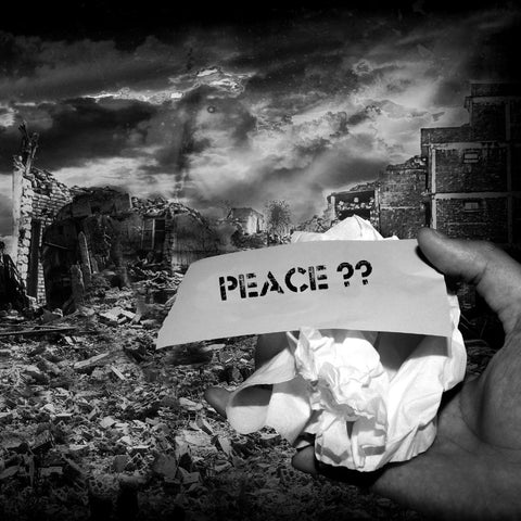 a war torn background with a screwed up piece of white paper saying peace