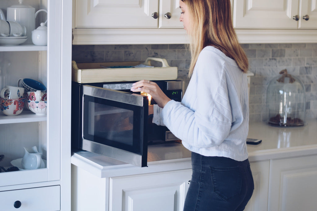 young teenage girl warming food in microwave
