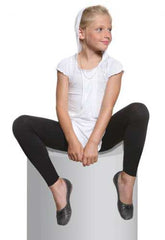 Girl sitting, wearing black footless tights, ballerina flats and white top.
