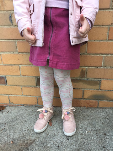 Child's lower body, standing against a wearing various shades of pink.