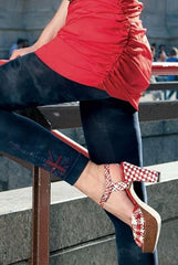 Side view of girl's legs in blue footless tights, pumps and a red top.