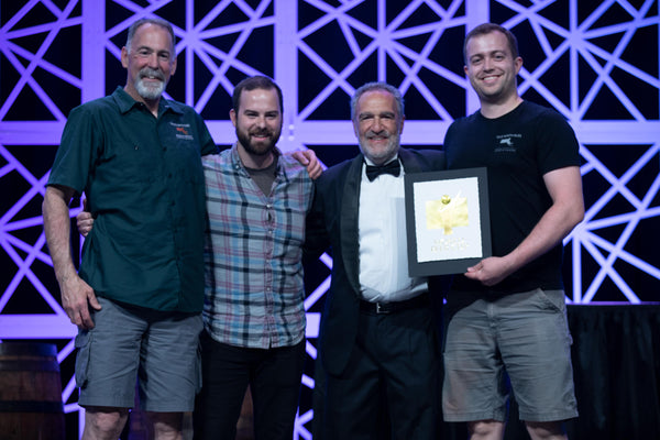 Founder Gary Rogers, Head Brewer Seth Barnum, and Founder Jake Rogers receiving the Gold Award for Vincianne, a Belgian Blonde Ale, from Charlie Papazian at the 2018 World Beer Cup