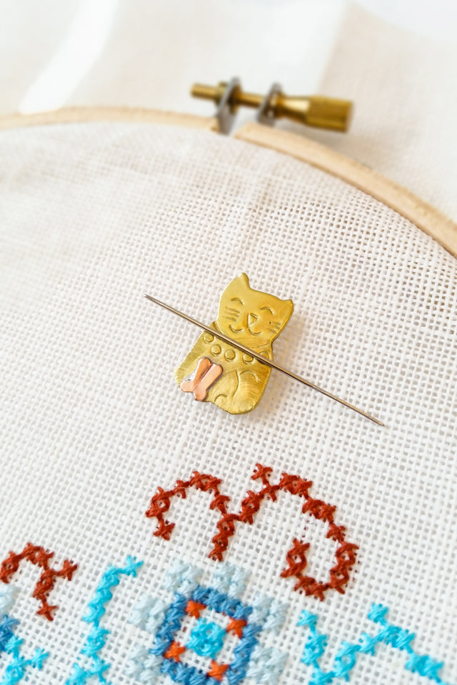 How to use a needle minder for cross stitch and embroidery - Stitched Modern