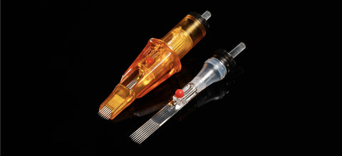 Two Peak Triton cartridge needles, one enclosed in orange plastic, and one stripped down to the bar needle; both of them show the red plunger ball stabilizing mechanism