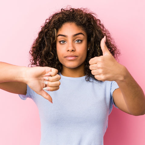 Girl in full makeup giving a thumbs up and thumbs down 