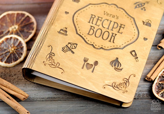 Wooden engraved cover of a personalized cookbook laying on table