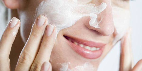 Woman rubbing lotion on her face and smiling