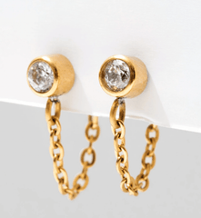 gold bezel set gemstone earrings with a gold hanging chain. earrings are hanging on a white background.