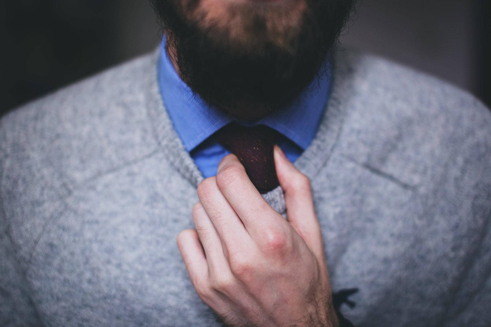 A man wearing men’s casual office wear adjusting his tie