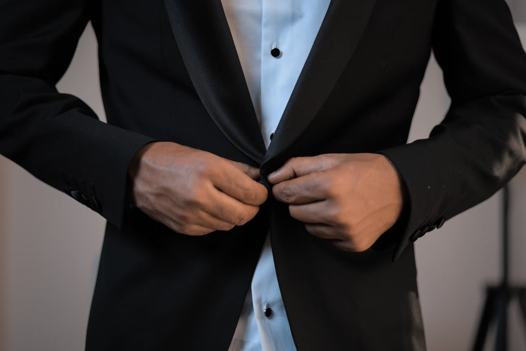 A man buttoning a black tuxedo