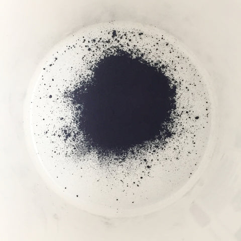 natural organic indigo powder in a bucket is so dark it looks almost black