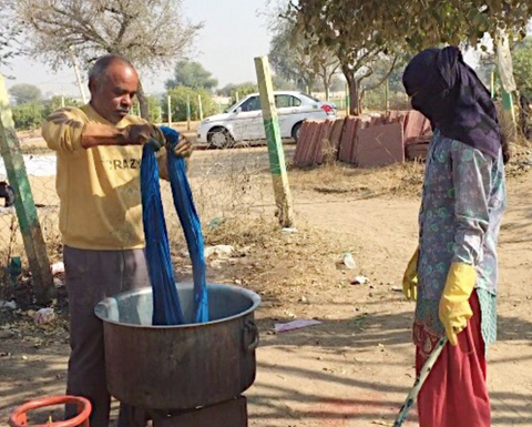 fabric being dyed by hand outside in a small pot