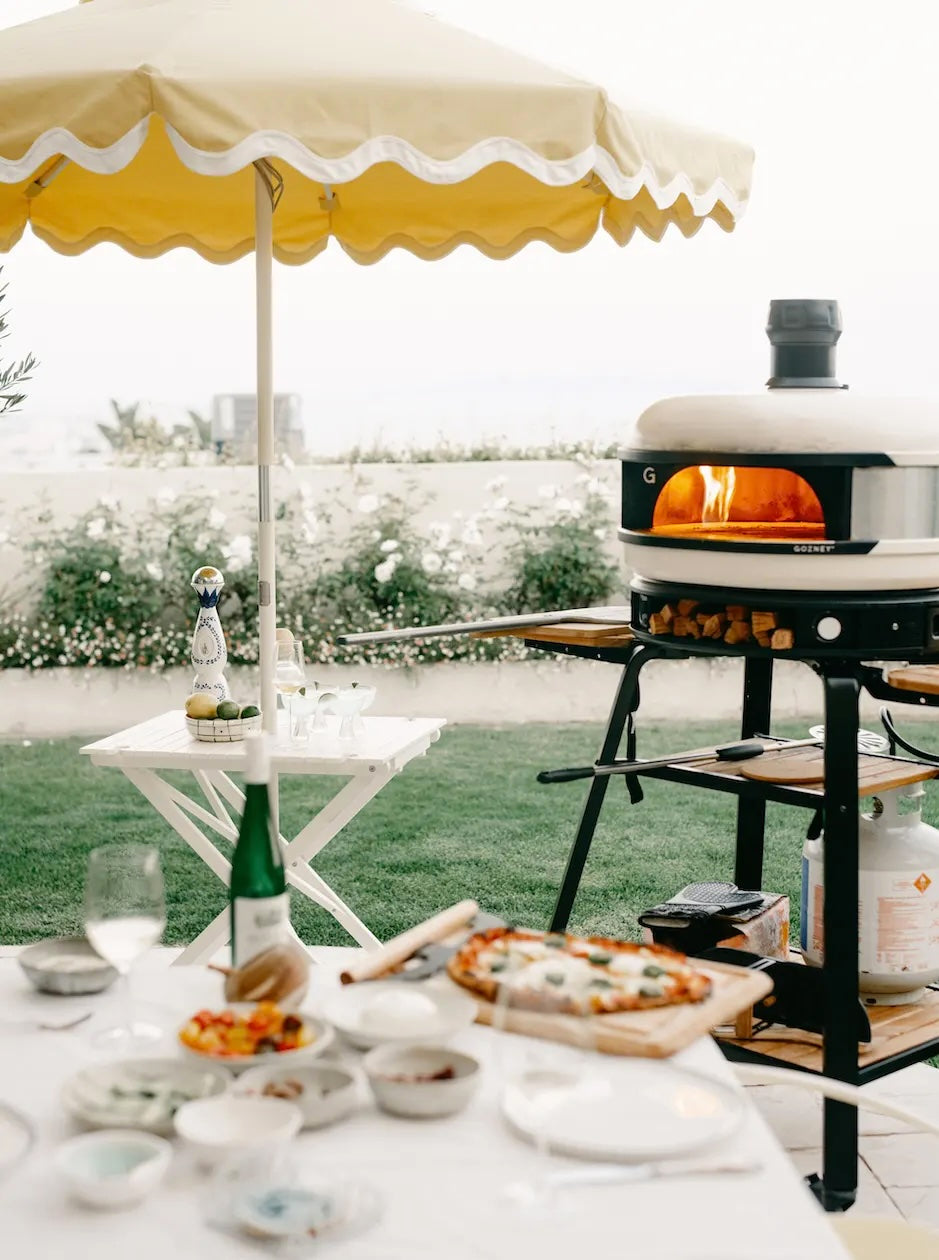 Yellow umbrella and Gozney pizza oven in a backyard