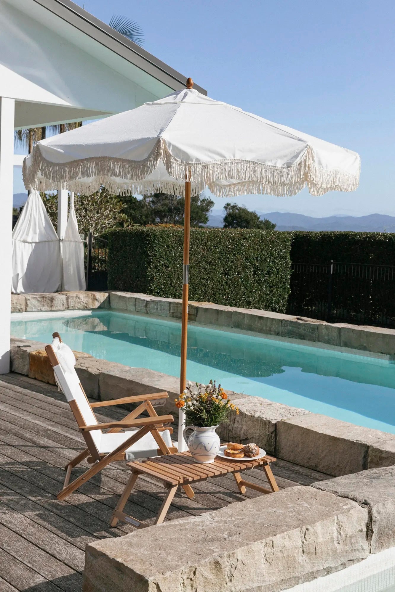 White market umbrella and tommy chair poolside