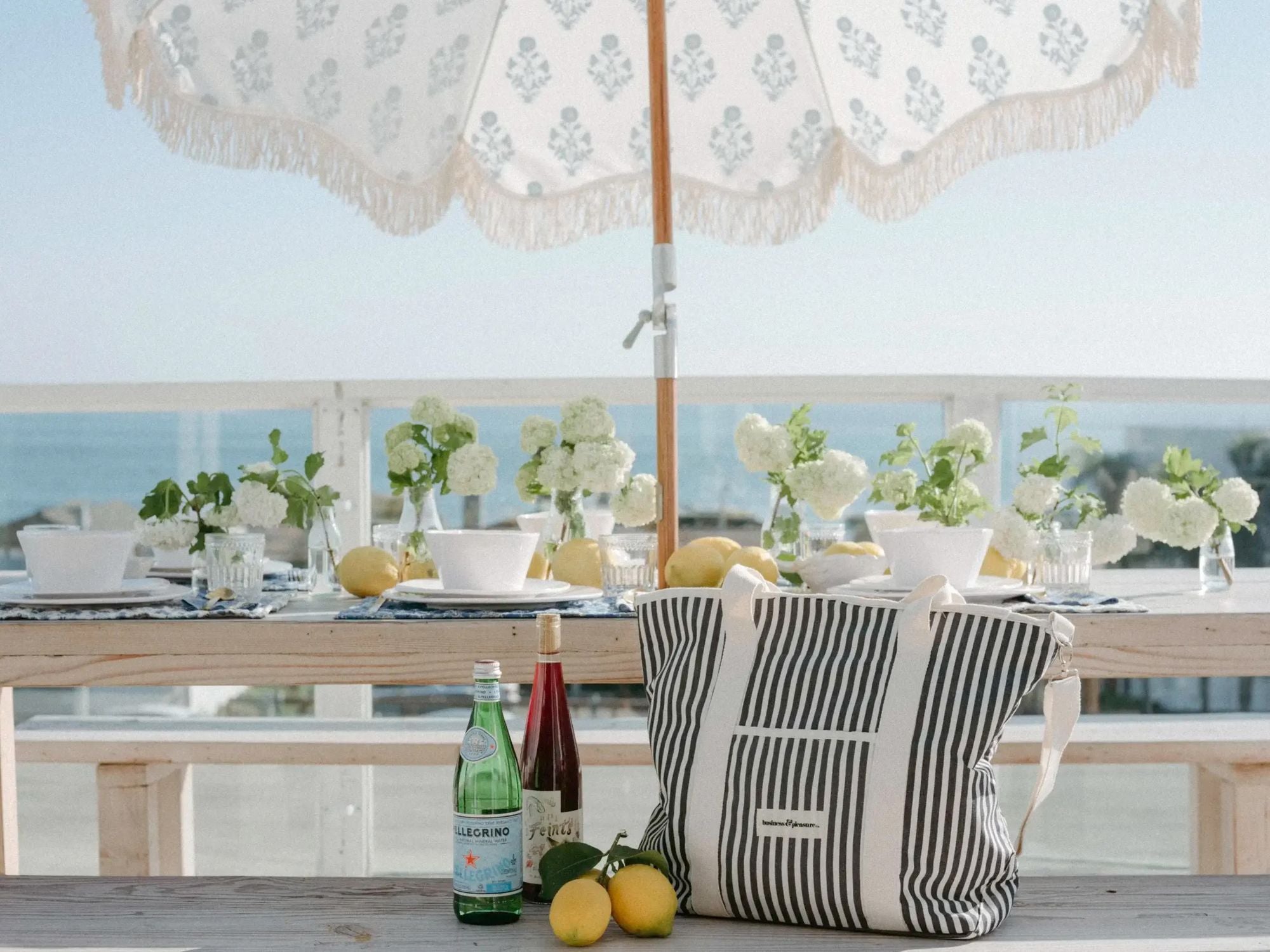 Outside table and umbrella with beverages and a cooler tote bag