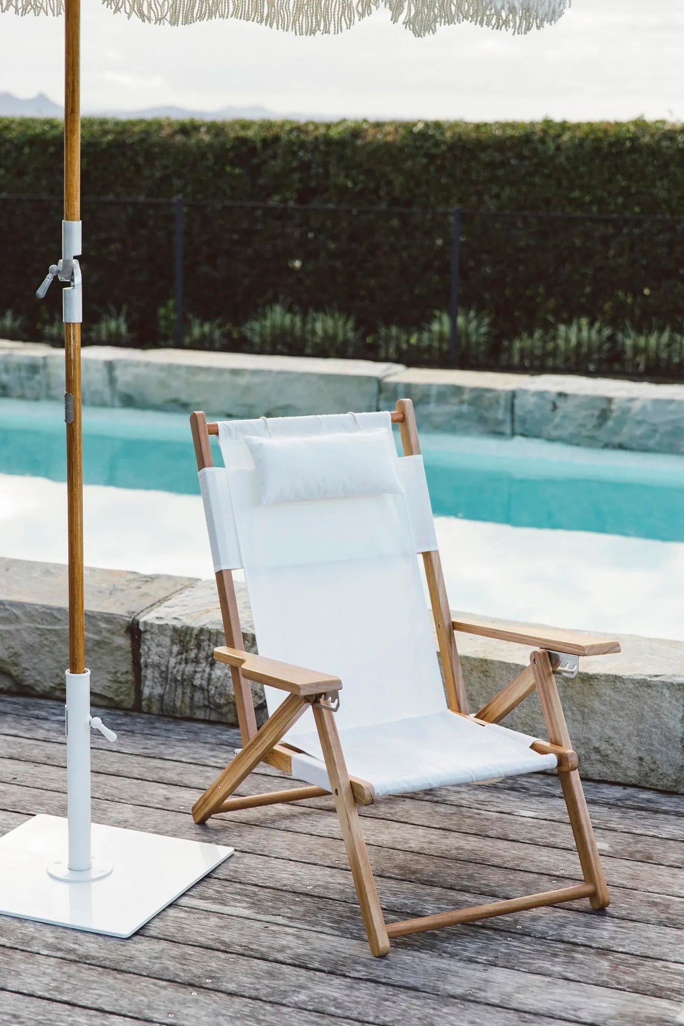 White premium beach umbrella with a white tommy chair by the pool
